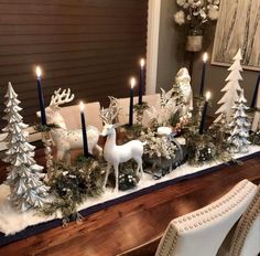 a dining room table decorated for christmas with candles and deer figurines on it