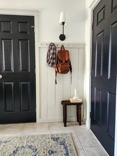 a room with two black doors and a brown backpack hanging on the wall next to it