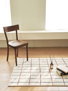 a wooden chair sitting on top of a white rug next to a book and brush