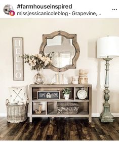 a living room with wooden floors and white walls, a mirror on top of the table