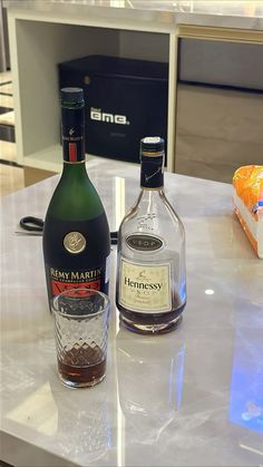 two bottles of liquor sitting on top of a counter next to an empty glass bottle