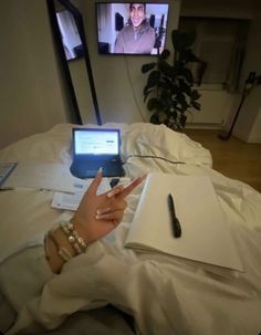 a person laying in bed with a laptop and cell phone on their lap, pointing at the screen