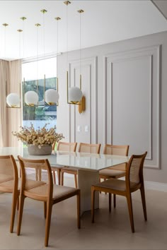 a dining room table with chairs and a vase filled with flowers on top of it