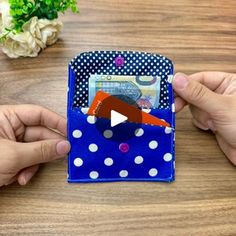 two hands holding a small wallet on top of a wooden table