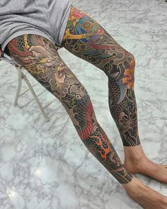 a man is sitting on a chair with his leg covered in tattoos