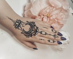 a woman's hand with a tattoo on it and a flower in the background