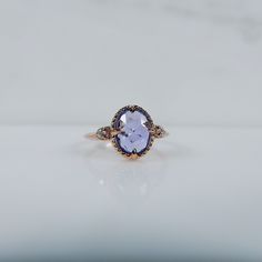 an oval shaped tan and blue stone ring on a white surface with the center stone surrounded by small diamonds