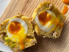 two pieces of bread with an egg in them on a cutting board next to other food items