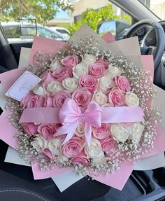 a bouquet of pink and white roses in a car