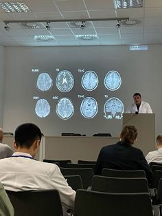 a group of people sitting in front of a projector screen with mri images on it