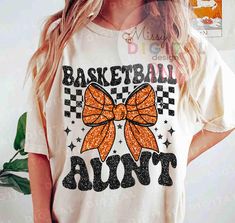 a woman wearing a white shirt with an orange bow on the front and black lettering that says basketball run't