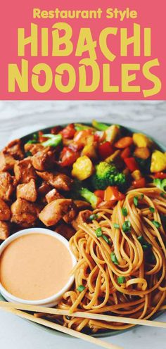 a plate filled with noodles, meat and vegetables next to dipping sauce on the side