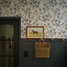 a painting hangs on the wall next to a basket with a horse drawn on it