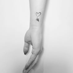 a person's hand with a small heart tattoo on the left wrist and an arrow in the middle