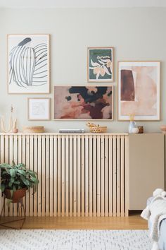 a living room with pictures on the wall and a plant next to it in front of a radiator