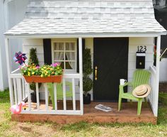 a small white house with green chairs and flowers