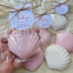 some pink and white seashells are wrapped in cellophane with thank you tags