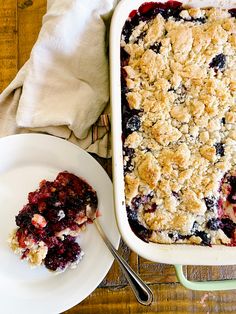 a blueberry crumbled dessert sitting on top of a white plate next to a fork