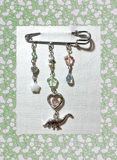 a brooch pin with charms hanging from it's side on a floral background