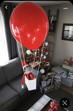 a living room decorated for christmas with presents and a large red balloon in the air