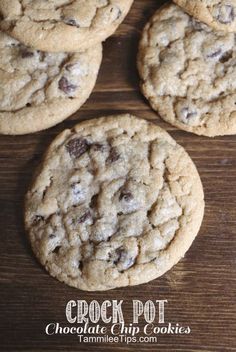 four chocolate chip cookies sitting on top of a wooden table