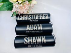 three black canisters sitting on top of a table next to a bouquet of flowers