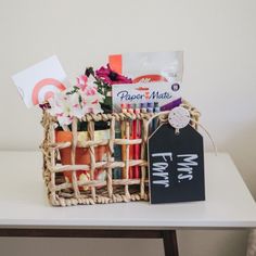 a basket filled with lots of different items on top of a white table next to a sign