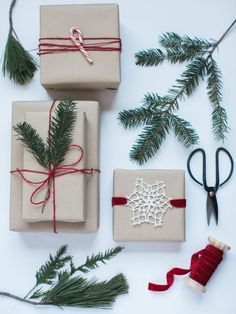 presents wrapped in brown paper and tied with red ribbon, pine needles, scissors and twine