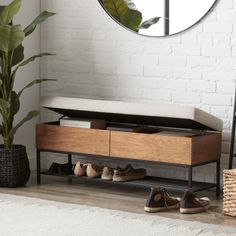 the shoe rack is next to a mirror and plant in a room with white brick walls