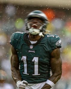 a close up of a football player wearing a uniform and holding a ball in his mouth