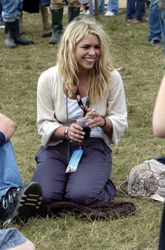 a woman sitting on the ground with her cell phone in her hand and people around her