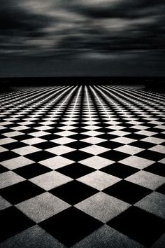 a black and white checkered floor with dark clouds in the background