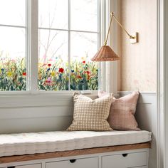 a window seat with two pillows and a lamp