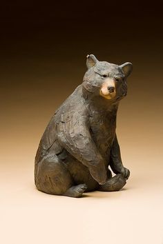 there is a statue of a bear sitting on the ground with its paws crossed and eyes closed