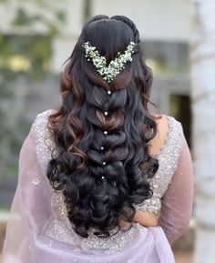 the back of a woman's head with long hair and flowers in her hair