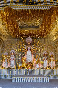 an elaborately decorated shrine with gold decorations and statues on the front wall, surrounded by golden chains