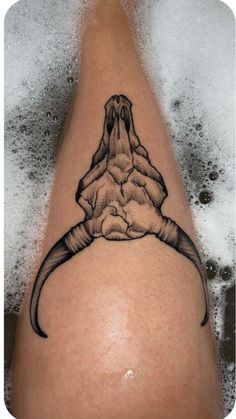 a tattoo on the leg of a person with a long tail and large horns in it