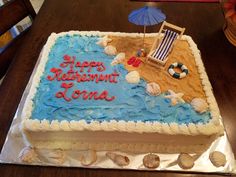 a birthday cake that is sitting on top of a table with an umbrella and beach chair