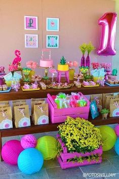 a birthday party with pink and blue decorations on the table, yellow flowers in vases