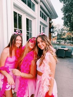 three girls dressed in pink posing for the camera outside a building with their arms around each other