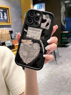 a woman holding up her phone case with an image of a heart