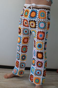 a close up of a person wearing colorful crochet pants with his legs crossed