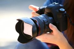 a woman is holding a camera and taking a picture with her thumb on the lens