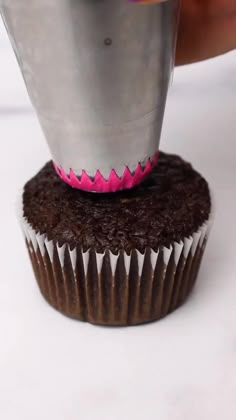 a cupcake being decorated with pink icing