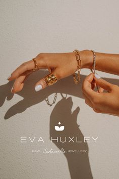 two hands with rings and bracelets on their fingers, one holding the other's hand