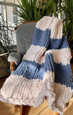 a blue and white blanket sitting on top of a chair next to a potted plant