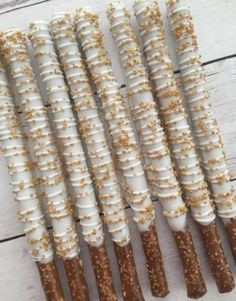 several sticks are lined up on a white wooden surface with gold sprinkles