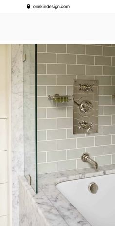 a white sink sitting under a bathroom mirror next to a tiled wall in a bathroom