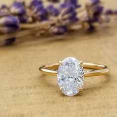 a close up of a ring on a table with lavender flowers in the back ground