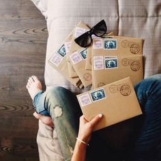 a person sitting on a couch with some mail in front of them and a pair of black sunglasses